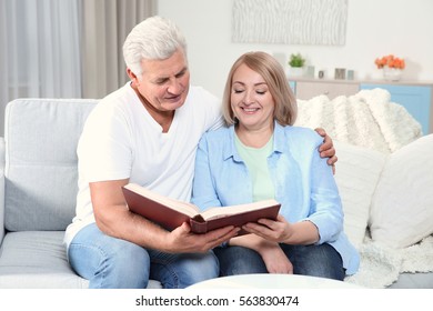 Grandparents Looking Through Photo Album At Home