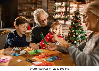 Grandparents making decorations with their grandchildren at home during Christmas and the new year holidays - Powered by Shutterstock