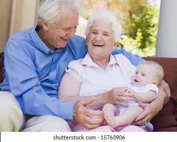 Grandparents Outdoors On Patio With Baby Smiling