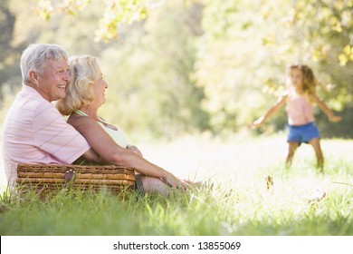 Grandparents at a picnic with young girl in background dancing - Powered by Shutterstock