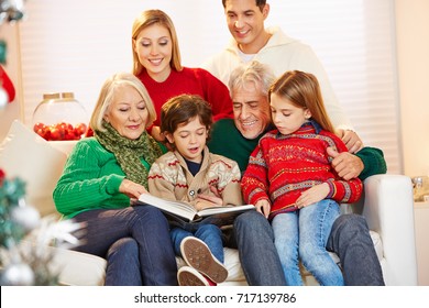 Grandparents Reading Book To Grandchildren At Christmas