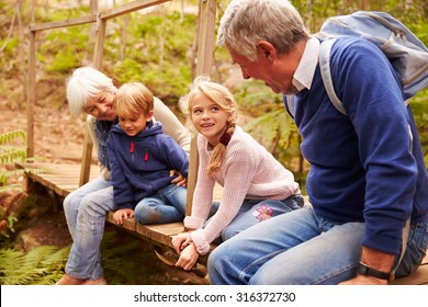 Grandparents Sitting With Grandkids On Wooden Bridge