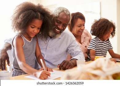 Grandparents Sitting At Table With Grandchildren Playing Games Together