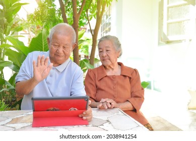 Grandparents Sitting And Using Smart Tablet(selective Focus) To Communicate With Their Son And Daughter Who Live Far Away, Concept Technology In Elderly People 