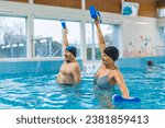 Grandparents taking care of their health. Senior adult caucasian married couple doing aqua fitness exercises with pool buoys. High quality photo