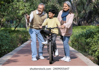 Grandparents teaching cycling to grandchildren in public park - Powered by Shutterstock