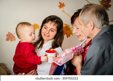 Grandparents With Their Small Grandchild Celebrating First Birthday At Home