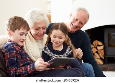 Grandparents Using Digital Tablet On Sofa With Grandchildren - Powered by Shutterstock