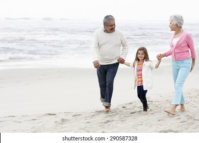 Grandparents Walking Along Beach With Granddaughter