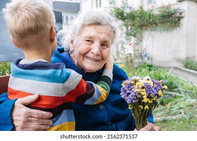 Grandson boy giving a flower to grandma. Grandson and grandmother spending time together. Granny with grandsons enjoying time together outdoor - Powered by Shutterstock