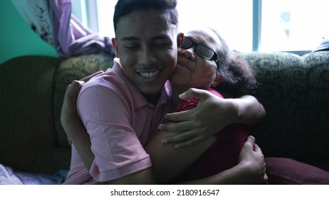 Grandson Embracing Grandmother At Home. Two Hispanic Family Members Hugging Each Other. Real Life And Authentic