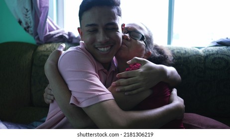 Grandson Embracing Grandmother At Home. Two Hispanic Family Members Hugging Each Other. Real Life And Authentic