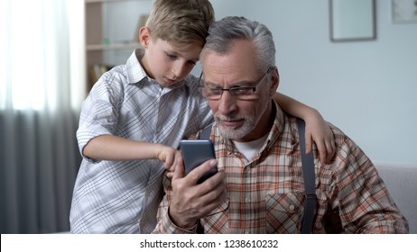 Grandson explaining grandpa how to use smartphone, easy application for elderly