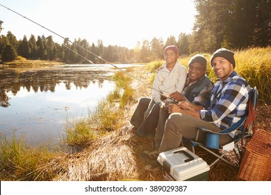 Grandson With Father And Grandfather Fishing By Lake