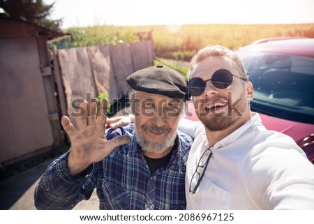 Grandson and grandfather man make selfie background of car, summer village with glare of light.