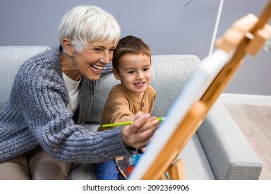 Grandson and grandma painting on canvas. Artist teaching young boy how to paint at home. Happy grandmother and a little boy painting. Senior woman with child painting on canvas.  - Powered by Shutterstock