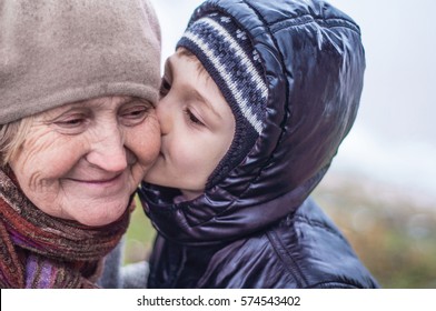 Grandson kisses his grandmother. Older woman and little boy close-up