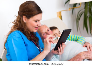 Grandson visiting grandmother in the nursing home, a young nurse spending time with them, holding a digital tablet. - Powered by Shutterstock