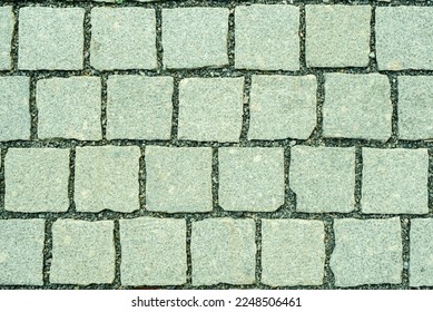 Granite cobblestone pavement background. Stone pavement texture. Abstract background of cobblestone pavement close-up. Seamless texture. View from above onto stone pavement of urban street. 