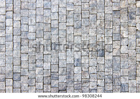 Granite cobblestoned pavement background. Full frame of regular square cobbles in rows. Natural stone textured background