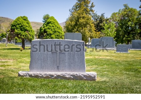 Granite headstone decorated with a large Christian cross at a cemetery