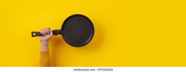 granite pan in hand over yellow background, panoramic image with space for text