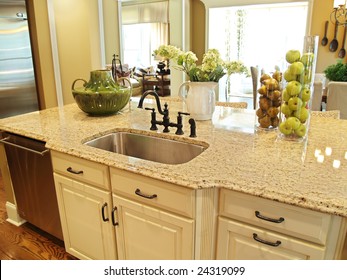 A granite topped island counter in a modern kitchen with dark hardware
