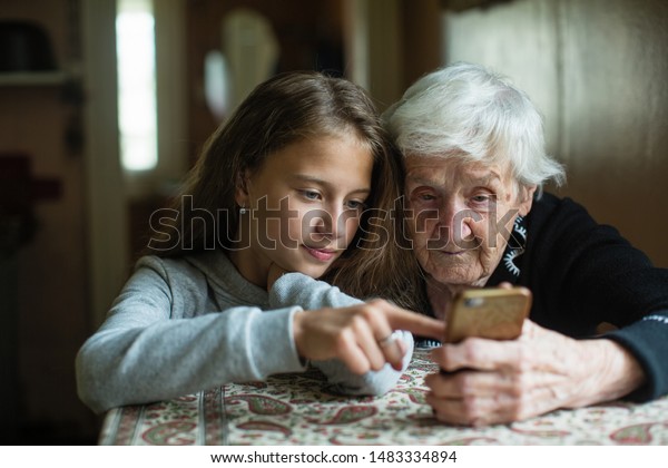 おばあちゃんと孫娘 可愛い女の子がおばあさんにスマートフォンを見せる の写真素材 今すぐ編集