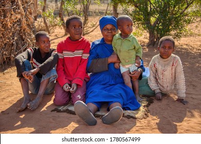 Granny And Kids, African Family, Sited In The Yard Of A Village In Botswana