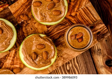 Granny Smith Apples With Smoothie Almond Butter With Whole Almond On The Top. Healthy Appetizers Apples With Peanut Butter On The Wood Table Background. Top View Snack On