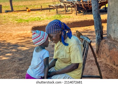 Granny telling a story to her granddaughter in the yard of a village in africa