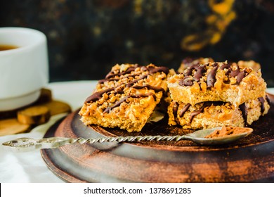 Granola bar cake with date caramel and chocolate. Healthy sweet dessert snack. Cereal granola bar with nuts, fruit and berries on a clay dark plate. Top view.