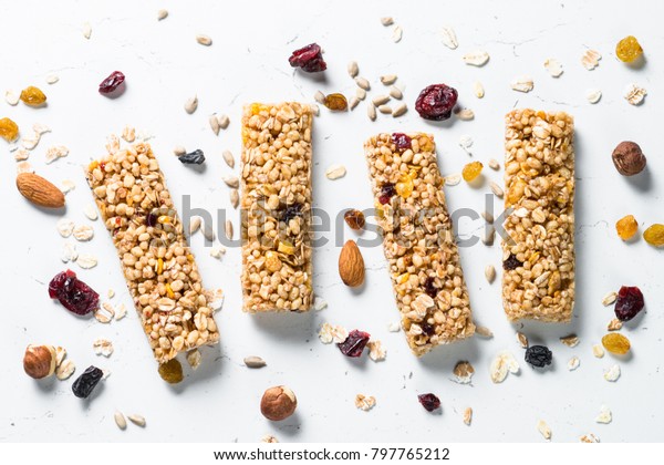 Granola bar. Healthy sweet dessert snack. Cereal\
granola bar with nuts, fruit and berries on a white stone table.\
Top view.