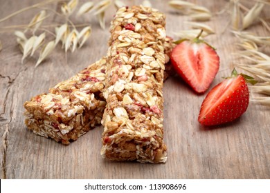 Granola bar with strawberries on wooden background