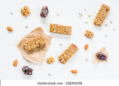 Granola bars, muesli bars or energy bars with oats, dates and nuts on white wooden background, top view. Snack for yoga, fitness and sports people - Powered by Shutterstock