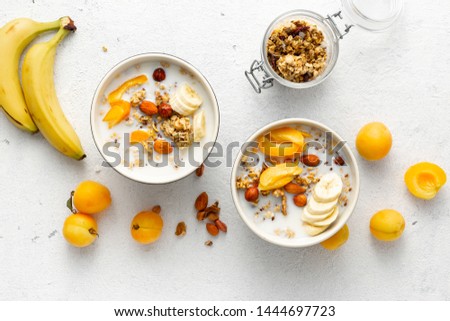 Granola breakfast with fruits, nuts, milk and peanut butter in bowl on a white background. Healthy breakfast cereal top view 