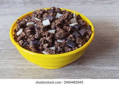 Granola with oatmeal and chocolate chips in a yellow plastic bowl on an oak table surface - Powered by Shutterstock