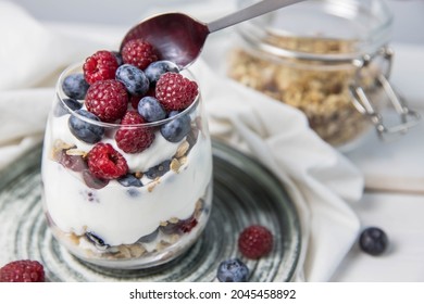Granola parfait with berries and yogurt with a copy space.  Parfait with granola , raspberries and blueberries on a white background with copy space. Granola in a glass . 