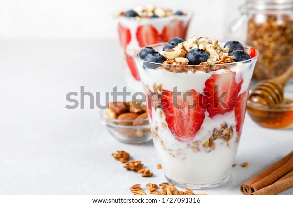 Granola Parfait with\
greek yogurt, oat granola, fresh berries, honey and mint leaves in\
tall glass jar. Healthy breakfast concept. Organic oat, almond and\
sunflower seeds.