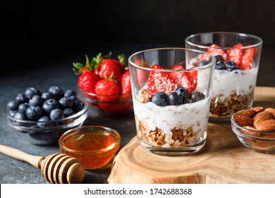 Granola parfait with homemade oat granola, fresh berries and greek yogurt in tall glass jar on dark blue background. Healthy breakfast concept. Organic oat, almond and sunflower seeds. - Powered by Shutterstock