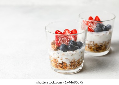 Granola parfait with homemade oat granola, fresh berries and greek yogurt in tall glass jar on white background. Healthy breakfast concept. Organic oat, almond and sunflower seeds. - Powered by Shutterstock