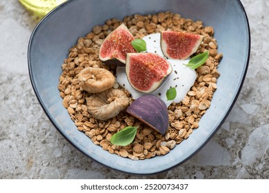 Granola served in a blue bowl with yogurt, fresh and dried fig fruits, horizontal shot, middle close-up, selective focus - Powered by Shutterstock