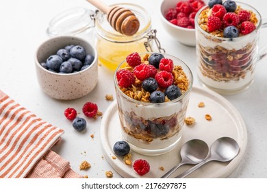 Granola with yogurt in glass served with fresh raspberry, blueberry and honey. Homemade oatmeal muesli. Vegetarian breakfast, healthy eating concept. Selective focus. - Powered by Shutterstock