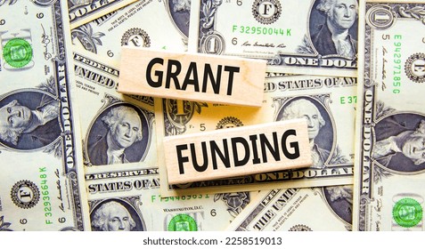 Grant funding symbol. Concept words Grant funding on wooden blocks. Beautiful background from dollar bills. Business and grant funding concept. Copy space.