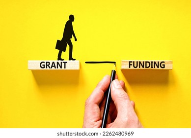 Grant funding symbol. Concept words Grant funding on wooden blocks. Beautiful yellow table yellow background. Businessman hand. Businessman icon. Business and grant funding concept. Copy space.