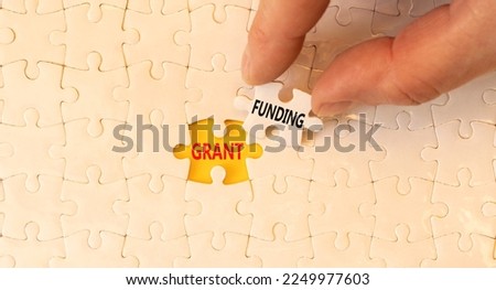Grant funding symbol. Concept words Grant funding on white paper puzzles. Beautiful yellow table white background. Businessman hand. Business and grant funding concept. Copy space.
