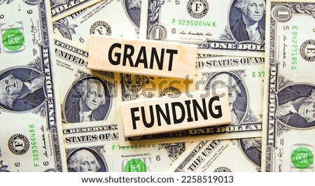 Grant funding symbol. Concept words Grant funding on wooden blocks. Beautiful background from dollar bills. Business and grant funding concept. Copy space.