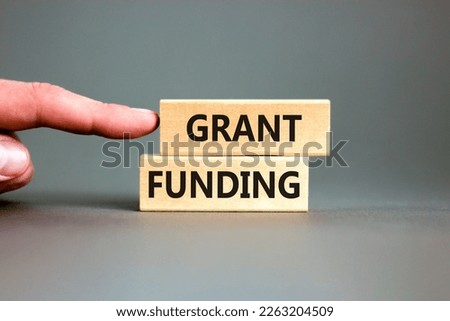 Grant funding symbol. Concept words Grant funding on wooden blocks. Beautiful grey table grey background. Businessman hand. Business and grant funding concept. Copy space.