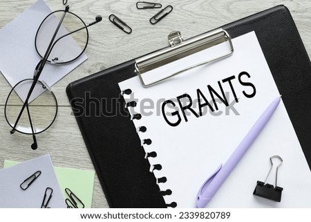 GRANTS page with text on folder with clip. purple sticker