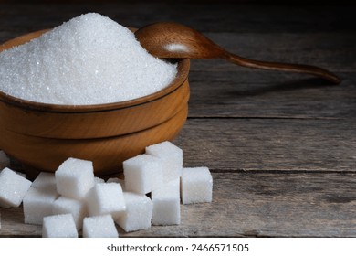 Granulated sugar in a wooden cup, a scattering of refined sugar cubes - Powered by Shutterstock